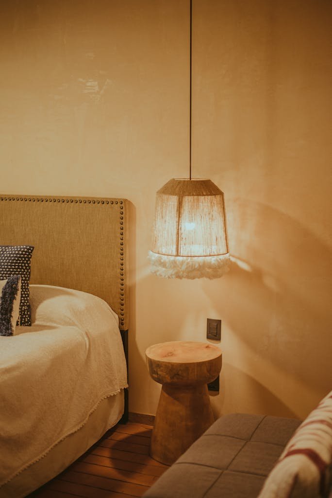 A cozy rustic bedroom featuring a bedside lamp, wooden table, sofa, and wooden floor for a warm ambiance.